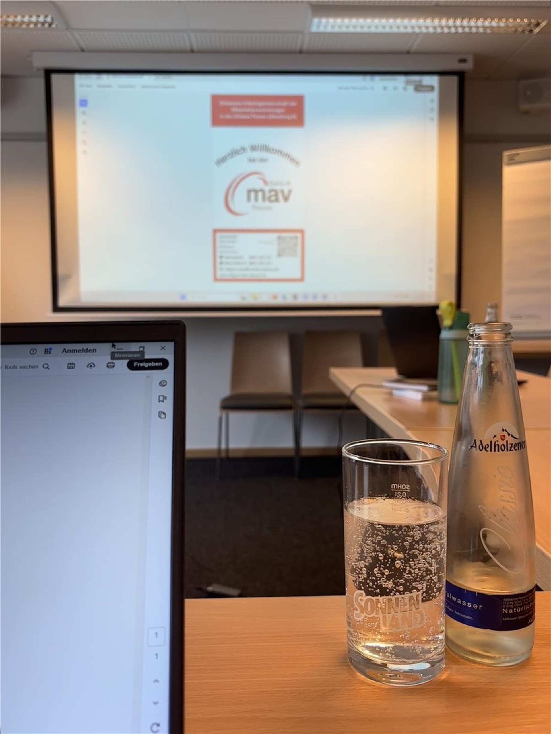 Ein Laptop und eine Wasserflasche stehen auf einem Tisch.